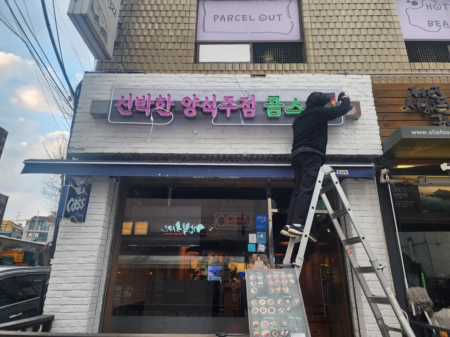 사다리 위에서 새 양식주점 간판을 설치하는 모습